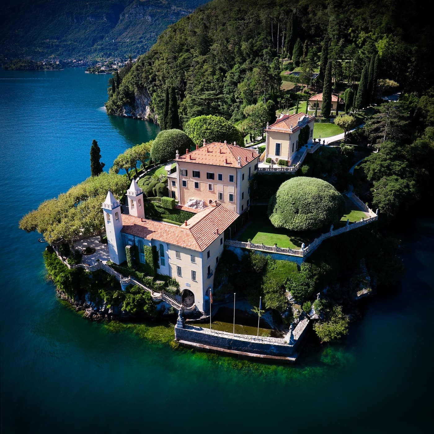 Aerial view of Villa del Balbianello and its gardens on the tip of the Lavedo peninsula, surrounded by the deep blue water of Lake Como
