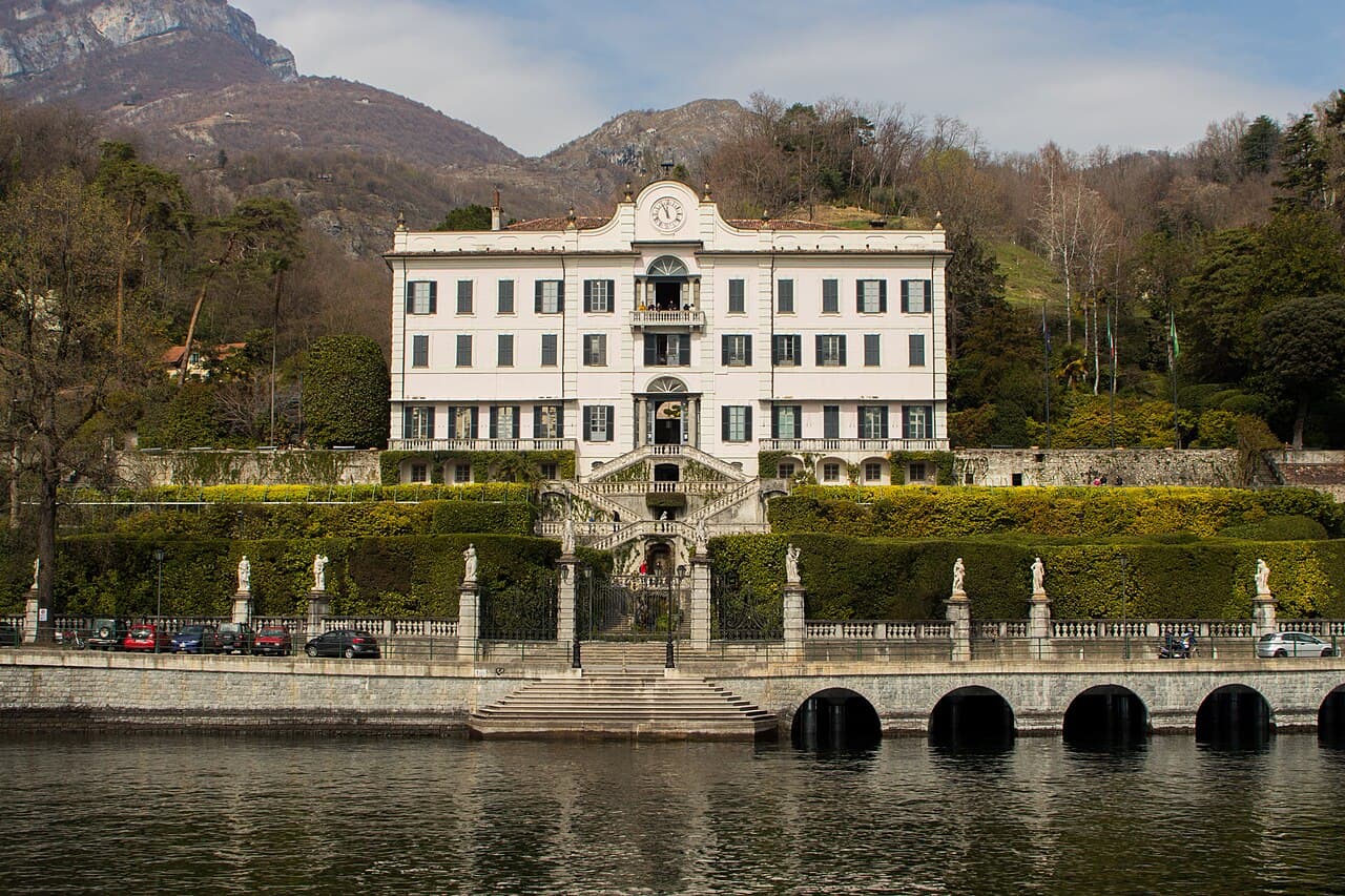A private Cranchi motorboat cruising past a lakefront villa on Lake Como on a clear morning